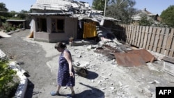 Жінка біля зруйнованого будинку в Авдіївці на Донеччині, серпень 2015 року
