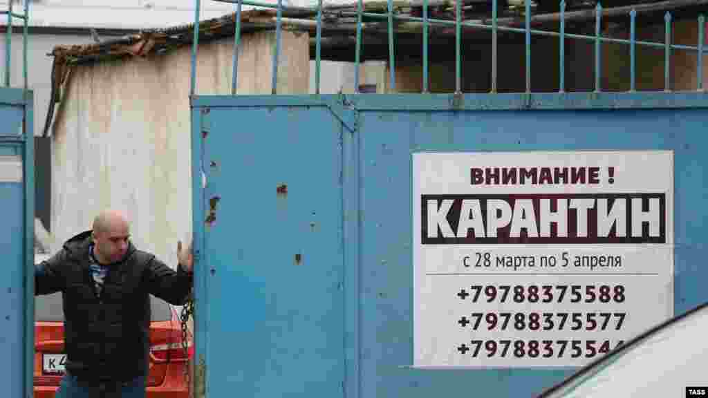 Aqmescitniñ sanayı alanındaki anbarlardan biriniñ araba qapusında asılğan karantin ilânı