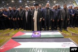 Верховный лидер Ирана Али Хаменеи руководит поминальной молитвой вместе с президентом Ирана Масудом Пезешкианом (в центре) над гробами убитого лидера "Хамас" Исмаила Хании и его телохранителя перед их похоронами в Катаре. Тегеран, 1 августа 2024 года