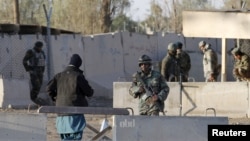 Afghan security forces stand guard on December 9 at the entrance gate of the airport near Kandahar that was stormed by the Taliban.