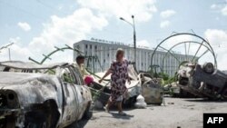 Жители Андижана проходят мимо сожженных автомобилей после столкновений, когда войска стреляли в демонстрантов.