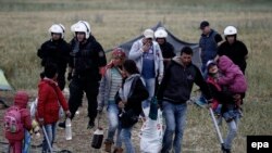 اعضای یک خانواده مهاجر در حالیکه وسایل شخصی‌شان را حمل می‌کنند، در حال ترک اردوگاه‌ ایدومنی‌اند 