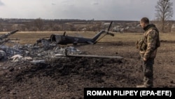 Украинский военнослужащий возле уничтоженного российского вертолета с буквой «Z», символом российского вторжения в Украину, в отбитой украинской армией деревне Малая Рогань возле Харькова, 31 марта 2022 года