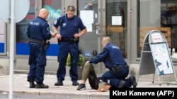 مأموران پلیس در حال امداد به یکی از زخمی‌شدگان حمله روز جمعه در تورکو