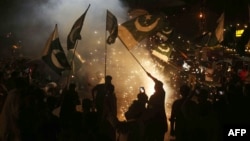 Pakistanis in Hyderabad wave flags as they celebrate after a cease-fire between Pakistan and India.