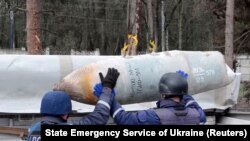 Фахівці Державної служби України з надзвичайних ситуацій (ДСНС) прибирають нерозірвану російську бомбу з місця падіння, очищаючи територію в Чернігові, 21 квітня 2022 року