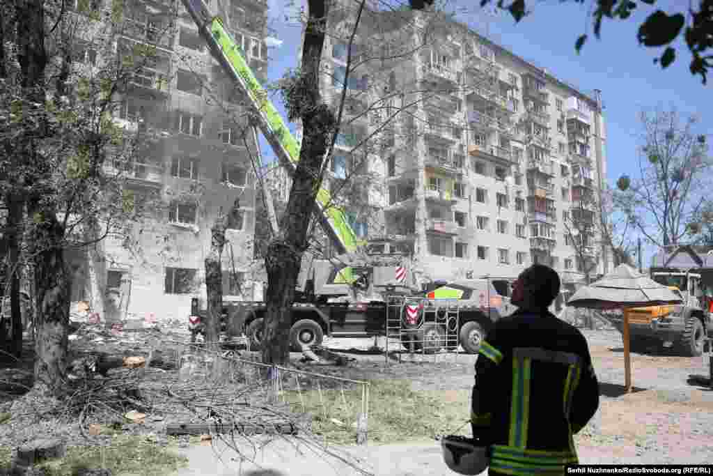 Один із рятувальників спостерігав за роботою техніки, що була задіяна в розборі завалів у Солом'янському районі Києва після влучення російської ракети в багатоповерхівку