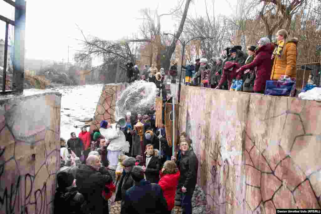 Чиркөө жетекчиси Виктор Реймген алардын башынан ылдый чакалап үч жолудан суу куюп жатты.