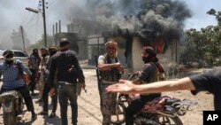 جنگجویان بَدَوی روز جمعه در برابر یک مغازه‌ٔ سوخته در روستای مزرعه در حومه‌ٔ شهر سویدا در جنوب سوریه گرد آمده‌اند