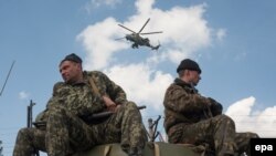 سربازان اوکراینی سوار بر خودروهای زرهی خود در شهر کراماتورسک، در حالی که هلی‌کوپتری بر فراز آنها در پرواز است.