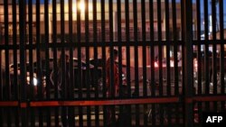 Люди стоять біля стіни, що розділяє США та Мексику. Калехіко, Каліфорнія