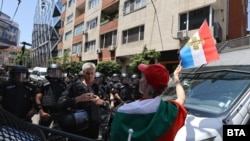 Протестиращ развява знаме пред служители на полицията, отцепили достъпа до сградата на ЕК в София.