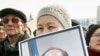 An opposition supporter holds a picture of Sarsenbaev days after his 2006 murder