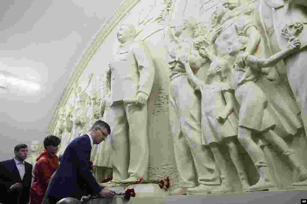 Таганская метросунда советтик лидер Иосиф Сталиндин элесин чагылдырган рельефтин алдына гүл койгон адамдар. Москва. 