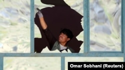 An Afghan man removes broken glass after a suicide bomb blast in Kabul in April.