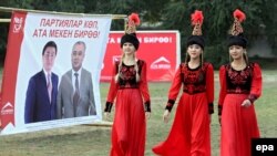 Gyrgyzystan, saýlaw plakatlarynyň öňünden geçip barýan gyzlar.