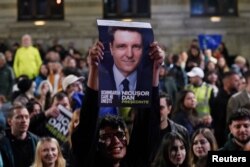 Un susținător al lui Nicușor Dan arată un portret al acestuia în seara alegerilor prezidențiale.