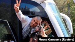 A freed Palestinian prisoner gestures in a bus after being released from an Israeli jail as part of a hostages-prisoners swap and a ceasefire deal in Gaza between Hamas and Israel.