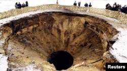 Журналісти та офіційні особи зі США, Росії та України оглядають воронку після підриву ракетної шахти в Первомайську в 1996 році. У червні 1996 року Україна перевезла в Росію останні 40 ядерних боєголовок і офіційно стала без'ядерною державою