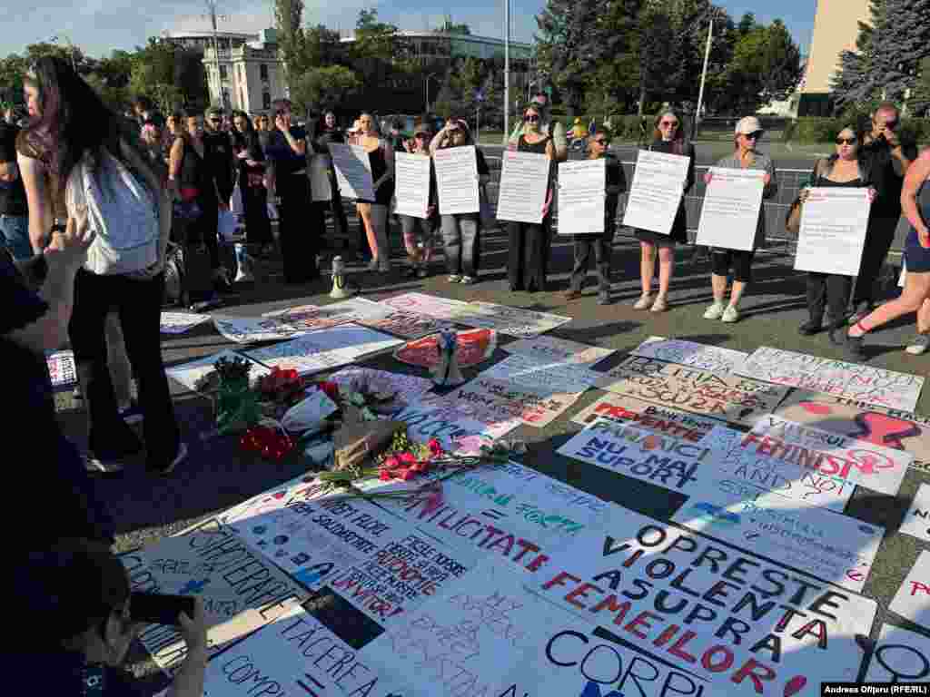 Протестувальники тримають плакати, які засуджують насильство над жінками та кладуть квіти в пам'ять про Теодору Марку. 31 травня 23-річну жінку застрелив, імовірно, її колишній хлопець, коли вона гуляла зі своєю 3-річною донькою. На той момент Теодора була на 26 тижні вагітності