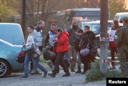 Цивільні жителі, евакуйовані з заводу «Азовсталь» у Маріуполі, йдуть у супроводі членів Міжнародного Комітету Червоного Хреста (МКЧХ) до пункту тимчасового розміщення в селі Безіменне. Донецька область, 6 травня 2022 року