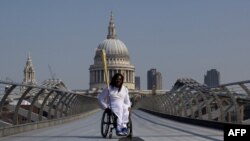 Британский баскетболист-паралимпиец Аде Адепитан везет олимпийский огонь по Мосту тысячелетия. Лондон, 26 июля 2012 года.