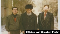 Кытайлык кыргыздардын залкар манасчысы Жусуп Мамай кыргызстандык Орозбүбү Сатиш кызы жана артыштык илимпоз Мамбеттурду Мамбетакун (сол жакта) менен. Үрүмчү шаары, 1997-жылдын ноябры