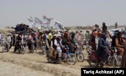 Taliban supporters fly the Taliban's signature white flag in the border town of Chaman, Pakistan, on July 14, after the militants claimed they had seized the crossing at Spin Boldak in Afghanistan.