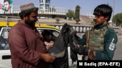 Kandagar. Owgan howpsuzlyk işgäri barlag nokadyna gelen geçegçini barlaýar. 12-nji awgust, 2021.