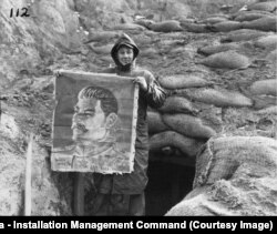 Корейская война 1950-53 годов: американский солдат позирует с портретом Сталина, найденным на захваченных позициях северокорейских войск и их китайских союзников