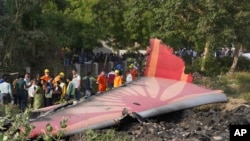 Хора са се събрали около останките на самолета, който се разби в северозападния индийски град Ахмедабад в щата Гуджарат на 12 юни.