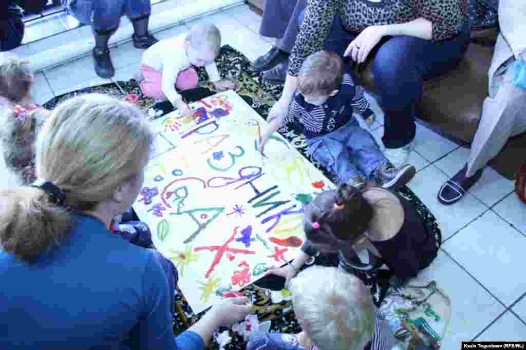 Бүлдіршіндер қылқаламмен сурет салып көріп жатыр.