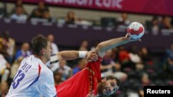 Испанский спортсмен Джон Канеллас (справа) и  сербский спортсмен Момир Илич Сербии во время матча мужского гандбола на Олимпийских играх в Лондоне, 29 июля 2012 года. 