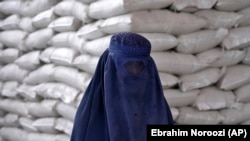 یک زن افغان در انتظار دریافت جیره غذایی در کابل. مه ۲۰۲۲