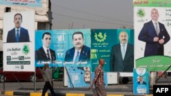 Баш калаа Багдаддын тургундары парламенттик шайлоону утурлай илинген үгүт көрнөктүрүнүн тушунан өтүп баратышат. 6-ноябрь, 2025-жыл.