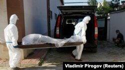 Медработники одного из дневных стационаров в Бишкеке выносят тело скончавшегося пациента. 6 июля 2020 года. 