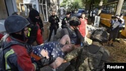 Рятувальники та співробітники поліції несуть на ношах мешканку, яка постраждала від російського авіаудару. Запоріжжя, 29 вересня 2024 року