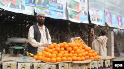 Продавец фруктов на фоне агитационных плакатов кандидатов в президенты Афганистана. Джелалабад, 3 февраля 2014 года.