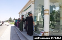 Aşgabadyň içi sowadyjyly awtobus duralgalarynyň biriniň daşynda duran ýolagçylar