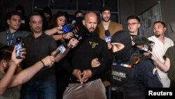 Эндрю Тейт жана бир тууганы Тристанды полиция алып кетүүдө.  