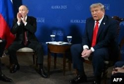 Володимир Путін (ліворуч) реагує на запитання про війну в Україні від іноземних журналістів під час церемонії фотографування з президентом США Дональдом Трампом в Анкориджі, штат Аляска, 15 серпня 2025 року