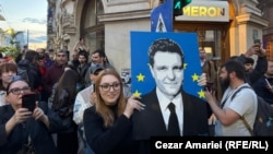 O susținătoare a lui Nicușor Dan ține în mână un portret al primarului general al Capitalei după afișarea rezultatelor exit poll.