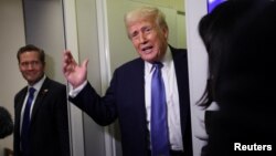 دونالد ترامپ در حالی که مایک والتز در کنار او ایستاده به سوالات خبرنگاران در هواپیمای ریاست جمهوری پاسخ می‌دهد