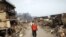 Japan -- A man covers his face as he walks through a destroyed residential area of tsunami-hit Otsuchi, 14Mar2011