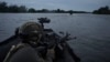 Ukrainian soldiers navigate on the Dnieper River by boat at the front line near Kherson.