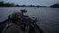 Ukrainian soldiers navigate on the Dnieper River by boat at the front line near Kherson.