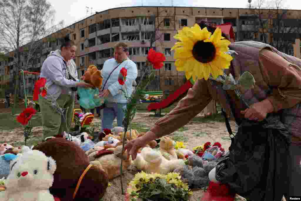 Люди скорбят и оставляют мягкие игрушки и цветы на детской площадке в месте, где произошел смертельный ракетный удар России по жилому району, в результате которого погибли несколько детей и взрослых. Кривой Рог, Украина, 5 апреля 2025 года. REUTERS/Violeta Santos Moura.