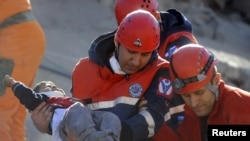 Куткаруучулар урандылар астынан тирүү тапкан жаш баланы тез жардам унаасына алып барууда. Түркиянын Эржиш району, 24-октябрь.