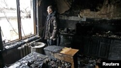 Місцевий житель дивиться з вікна у своєму будинку, пошкодженому обстрілами, Донбас, 30 березня 2017 року 