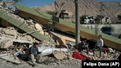 Люди біля зруйнованого землетрусом будинку в місті Дарбандіхан на півночі Іраку, 13 листопада 2017 року